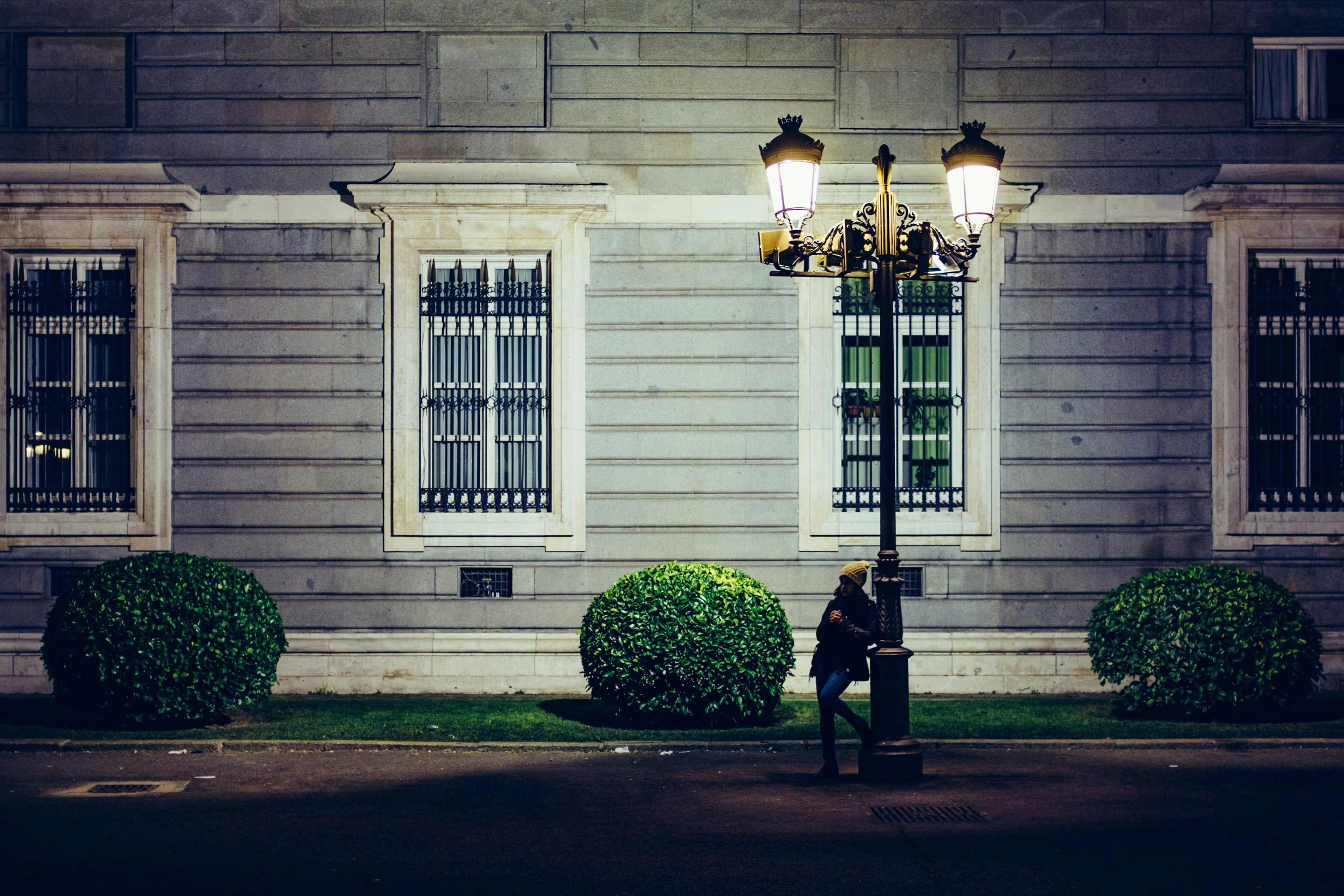 woman beside a lamppost at the alley near concrete building